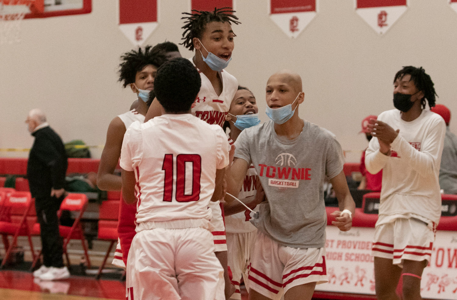 Teammates celebrate with Xavier Hazard (middle) who made a pair of big three point buckets to help the Townies defeat Hendricken during a D-I home match up on Thursday night.