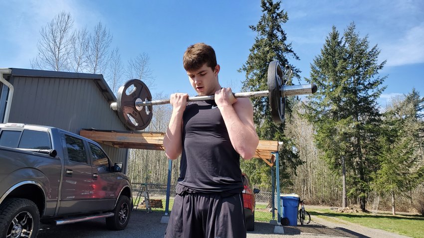Onalaska junior Kayden Allison lifts weight at his house near Mossyrock. Allison is one of many high school athletes in the county who are staying fit in hopes that spring sports returns this season. (Eric Trent / etrent@chronline.com)