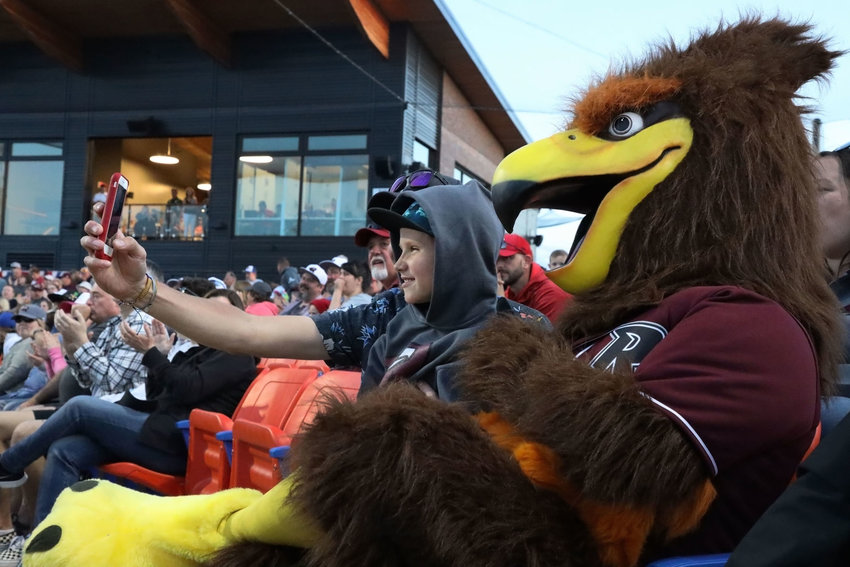 Noah Laible, of Vancouver, takes a selfie with his father Travis and Rally the Raptor during the Ridgefield Raptors&rsquo; opening game June 4. 2019.