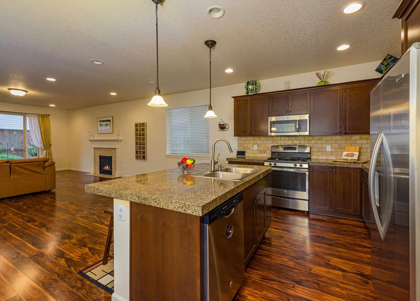 The kitchen space&nbsp;inside of the home at 351 N Green Gables Loop, Ridgefield, features granite countertops with slate and stainless steel appliances as well as laminated wood floors in an open concept area.
