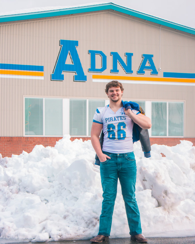 Lane Baker poses for a photo in his football jersey outside Adna High School Monday morning.