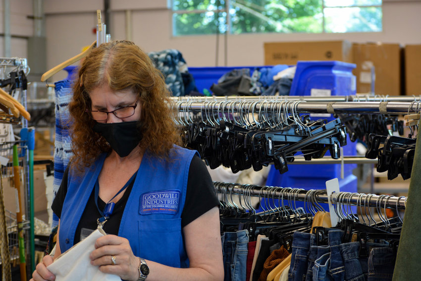 A Battle Ground Goodwill employee sorts linens in the back of the store on June 23.