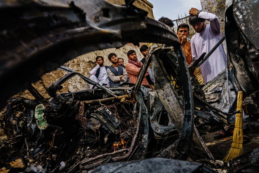 Relatives and neighbors of the Ahmadi family gathered around the incinerated husk of a vehicle targeted and hit earlier Sunday afternoon by an American drone strike, in Kabul, Afghanistan, Monday, Aug. 30, 2021. (MARCUS YAM / LOS ANGELES TIMES)