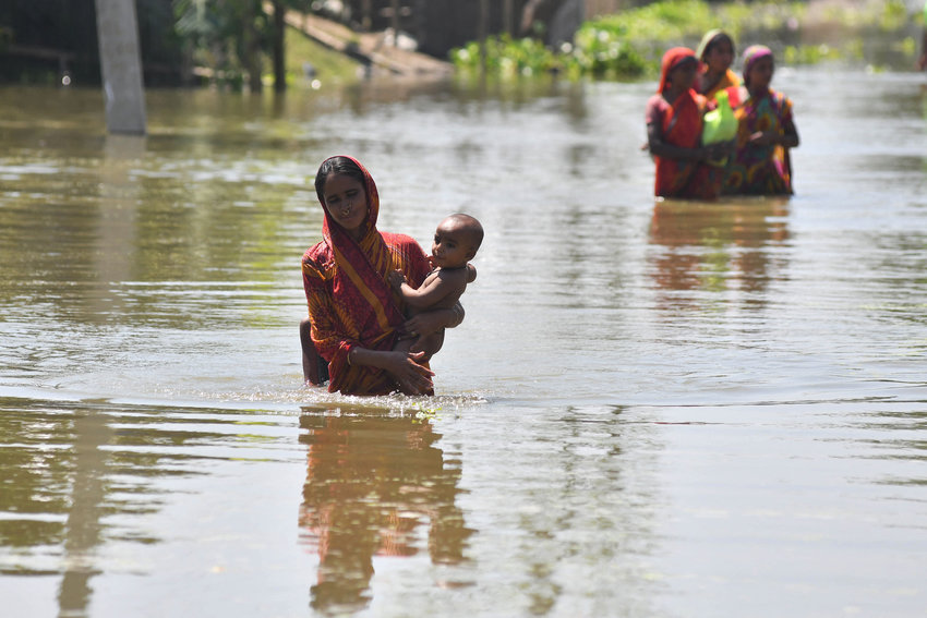 A woman carrying her child wades along a road in a flood affected area following heavy monsoon rainfalls in the Morigaon district in India's Assam state on Aug. 31, 2021. (Biju Boro/AFP/Getty Images/TNS)