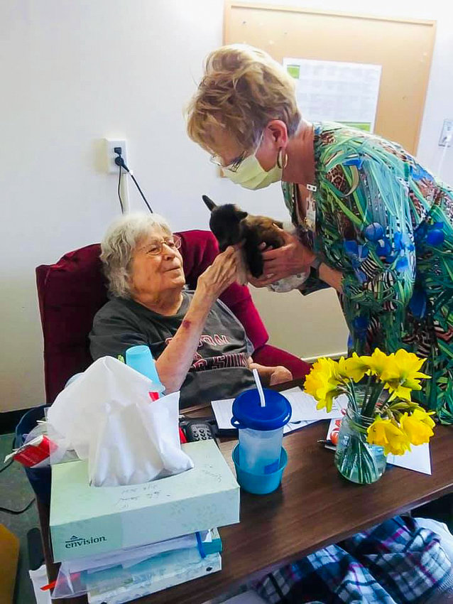 An employee at Woodland Care Center hands a cat to a resident.