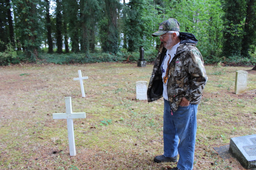 Mel Canfield pauses near a white, wooden cross he built and installed at the Newaukum Hill Cemetery. Many of the graves do not bear markers, potentially because the interred may have died at a local poor farm.