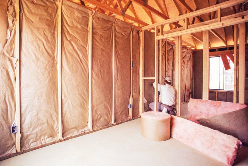 A man installs insulation at a house.